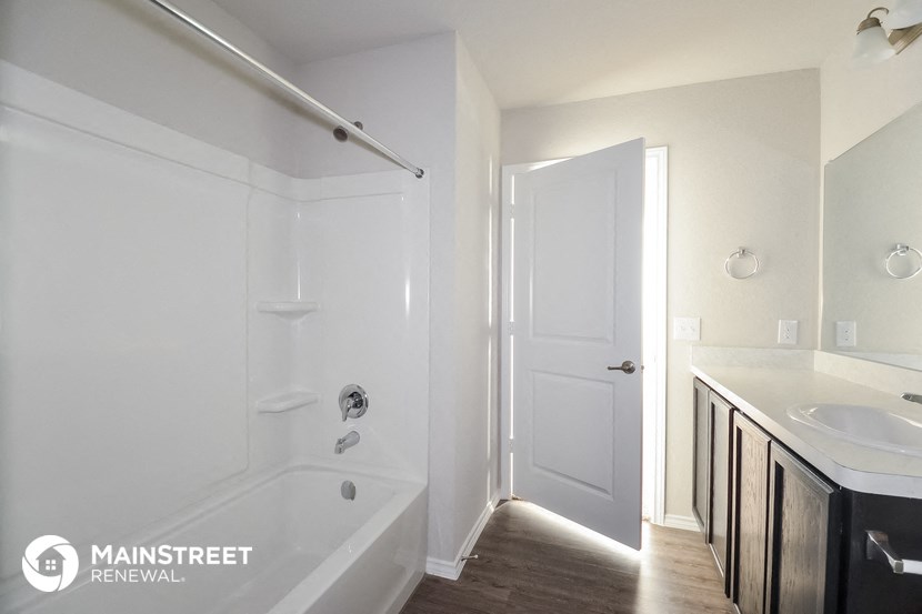 a bathroom with a tub and a sink and a white door