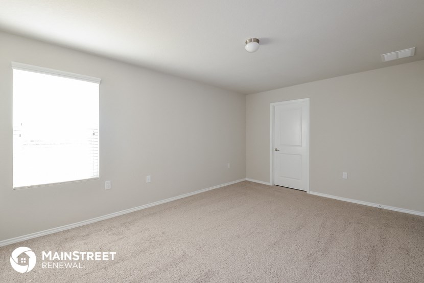 the spacious living room with white carpet and a white door
