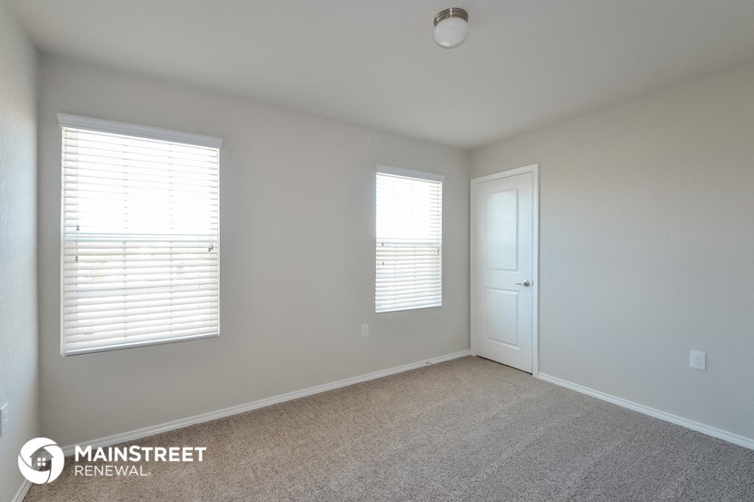 an empty room with two windows and a door