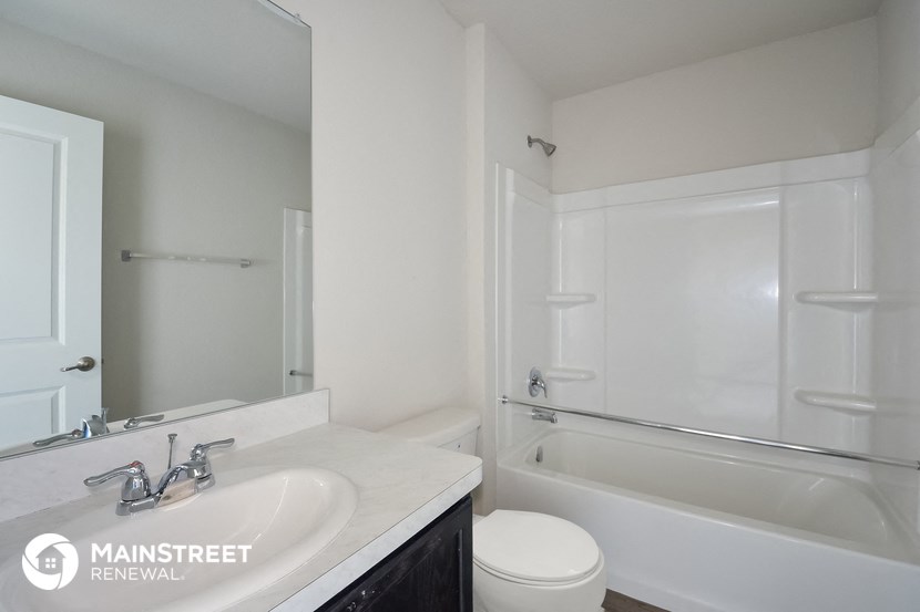 a white bathroom with a tub sink and toilet and a mirror