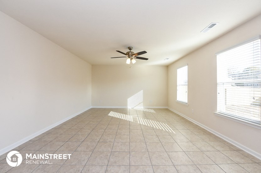 an empty living room with a ceiling fan