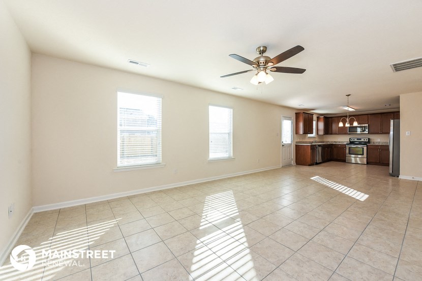 an empty living room and kitchen with a ceiling fan