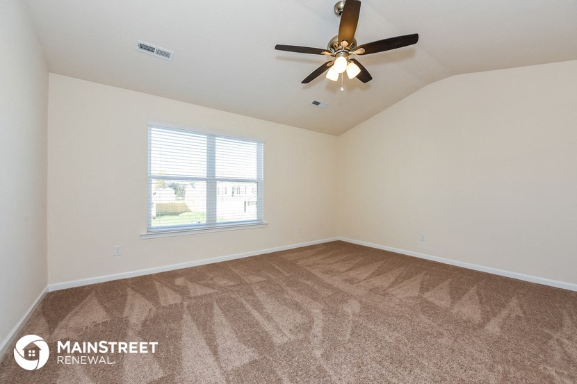 an empty living room with a ceiling fan and a window
