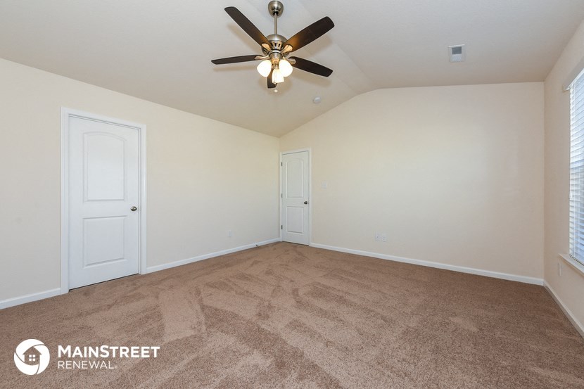 a spacious living room with carpet and a ceiling fan