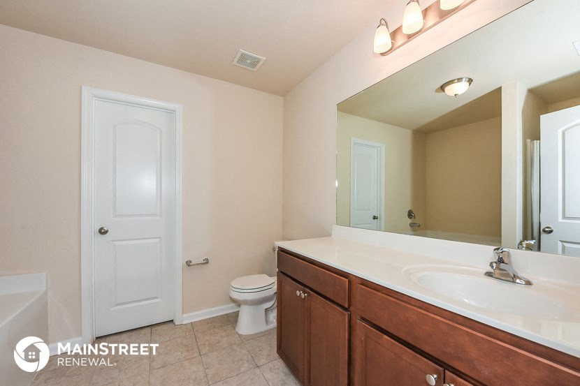 a bathroom with a large mirror and a sink and a toilet