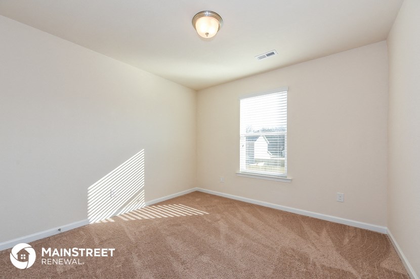 an empty living room with a window and a carpeted floor