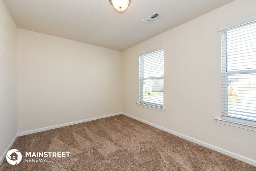 the spacious living room with carpeting and two windows