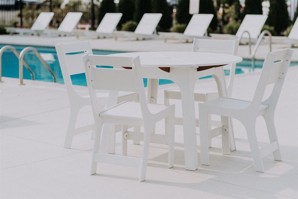 a white table and chairs next to a pool