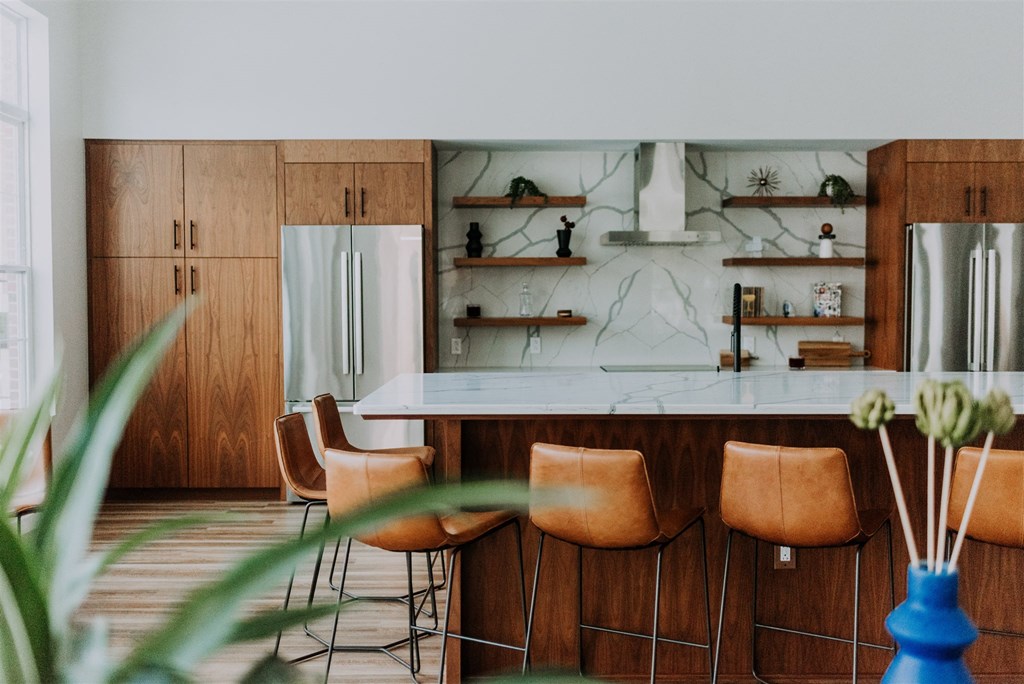 a kitchen with wooden cabinets and a marble counter and chairs
