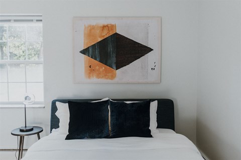 a bedroom with a bed and a painting on the wall