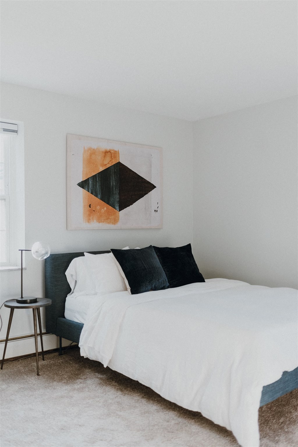 a bedroom with a bed and a painting on the wall