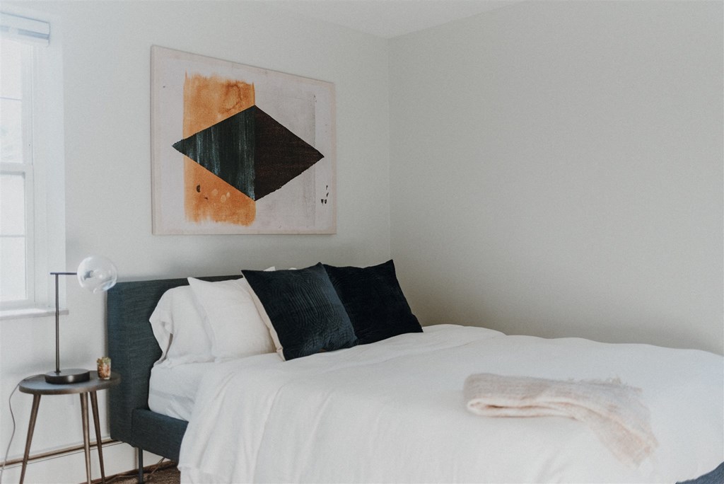 a bedroom with a bed and a painting on the wall