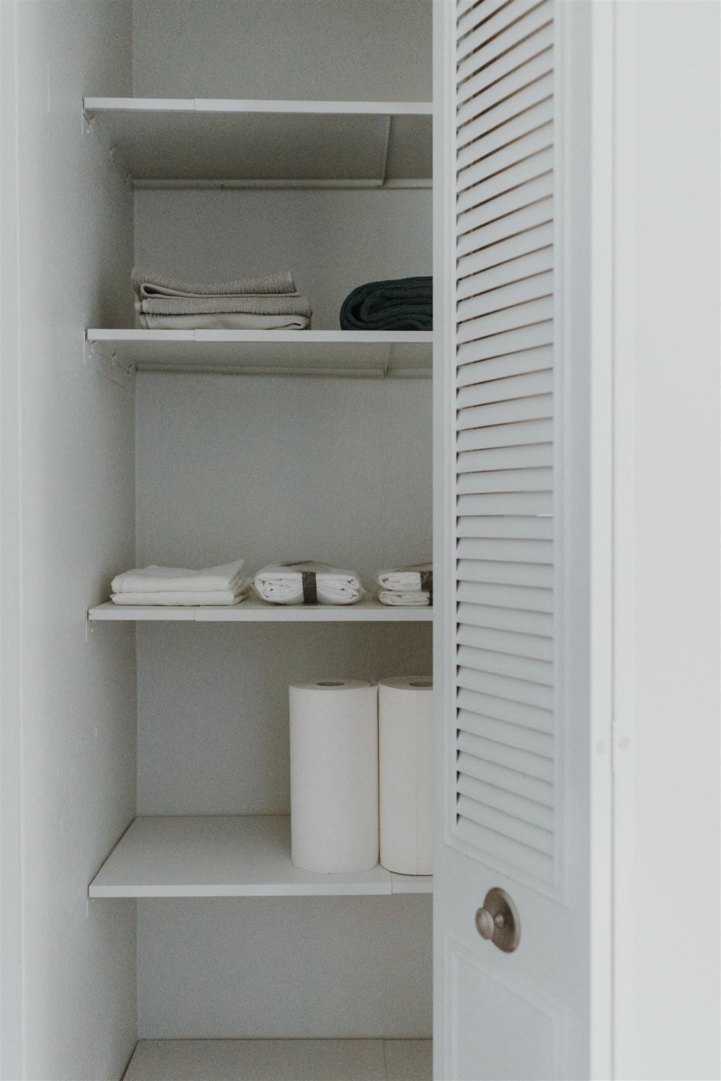 a small closet with shelves and toilet paper in it