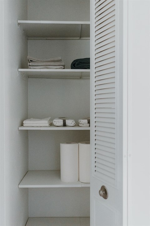 a small closet with shelves and toilet paper in it