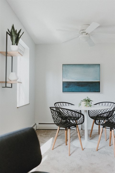 a dining room with a white table and chairs and a blue painting