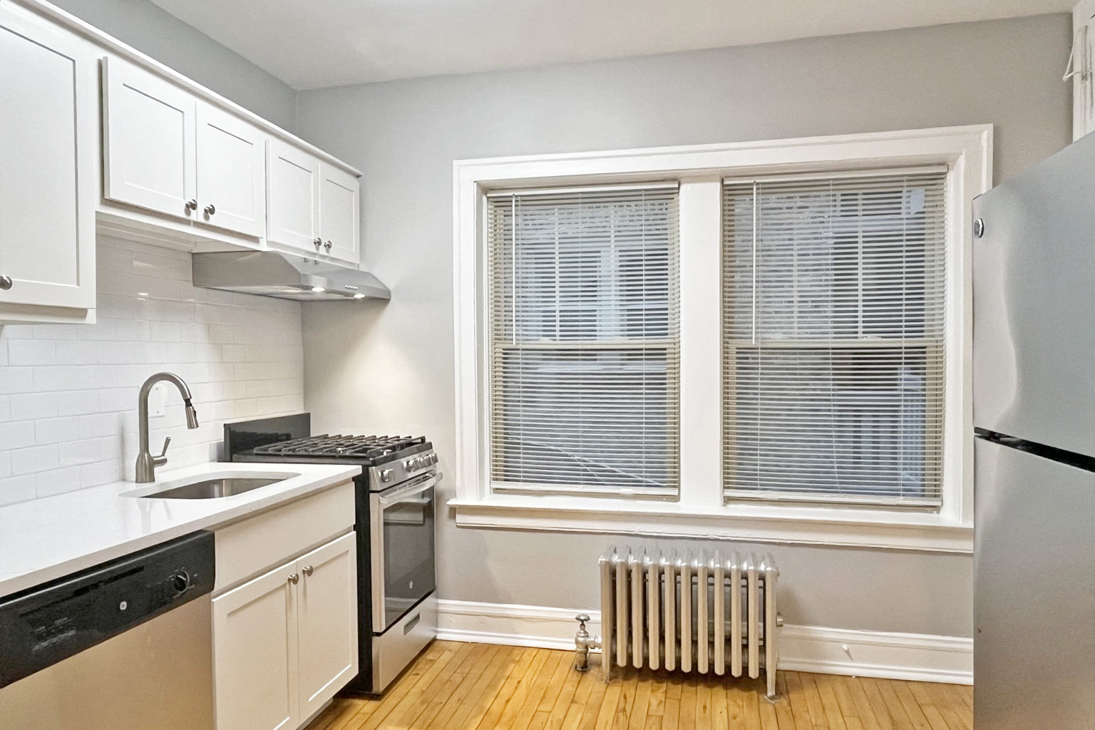 A kitchen with white cabinets and a stainless steel refrigerator.