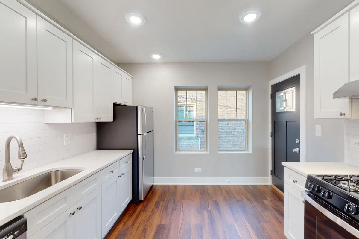 an empty kitchen with white cabinets and stainless steel appliances