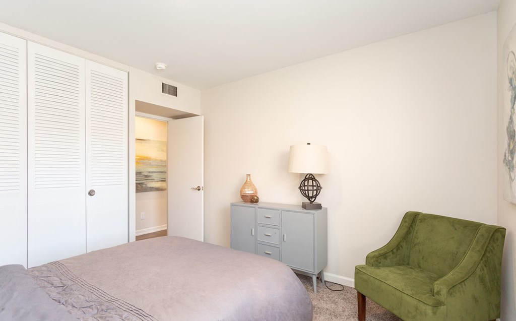 a bedroom with a bed and a chair and a closet