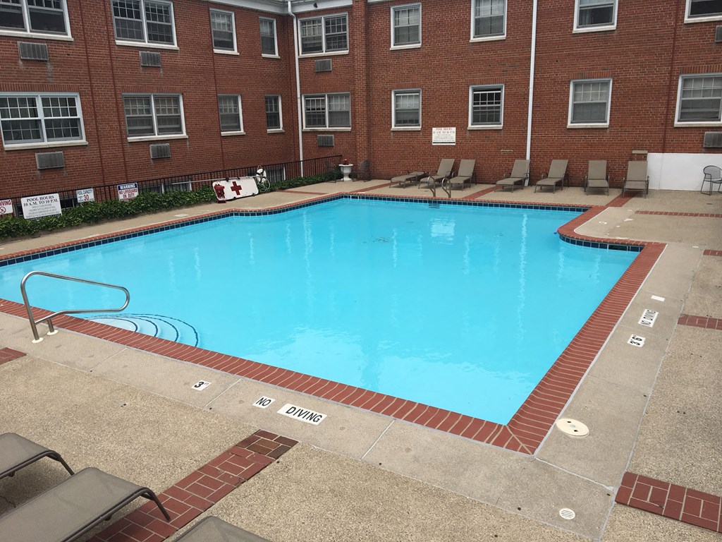 a large swimming pool in front of a brick building