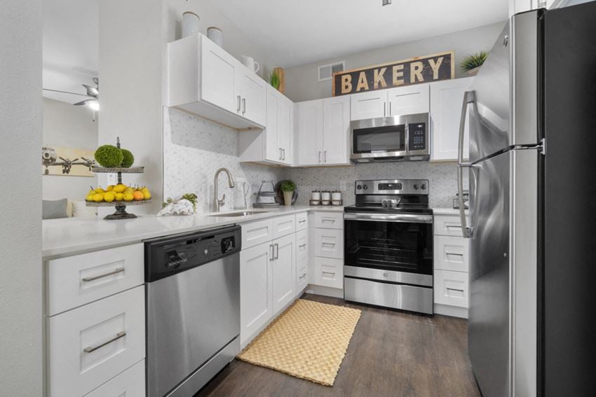 The Colony Apartments for Rent-Flatiron District at Austin Ranch Kitchen with Matching Stainless Steel Appliances, Stylish-TIle Backsplash, and White Cabinets