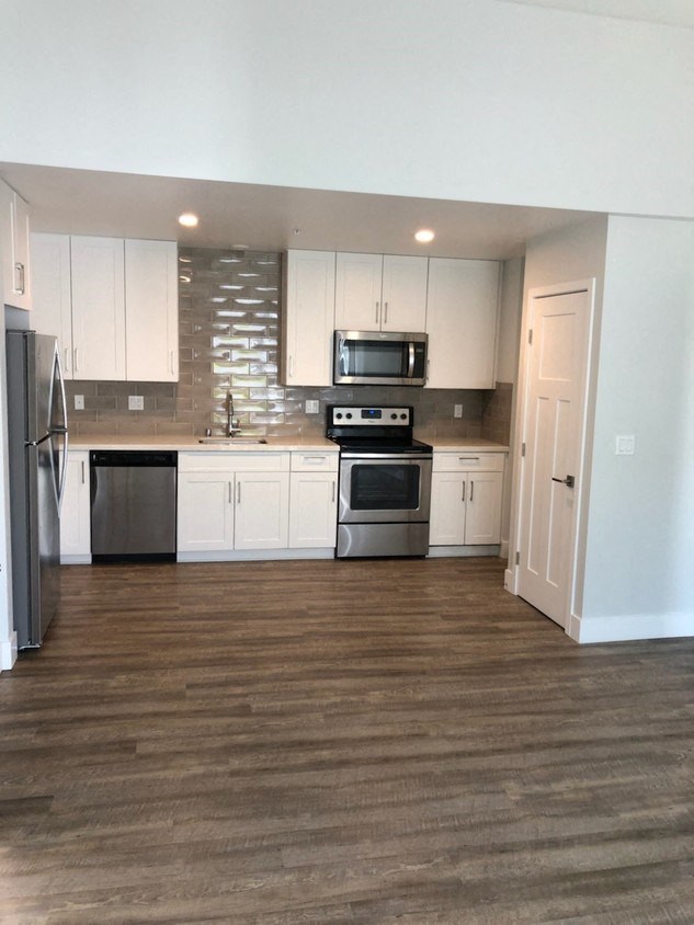 an empty kitchen with white cabinets and stainless steel appliances