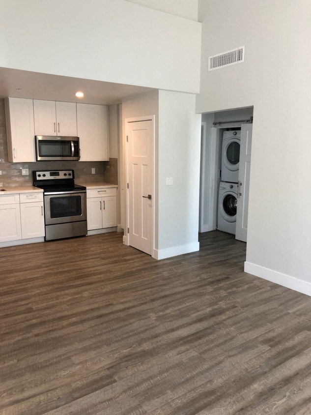 an empty kitchen with wooden floors and white cabinets