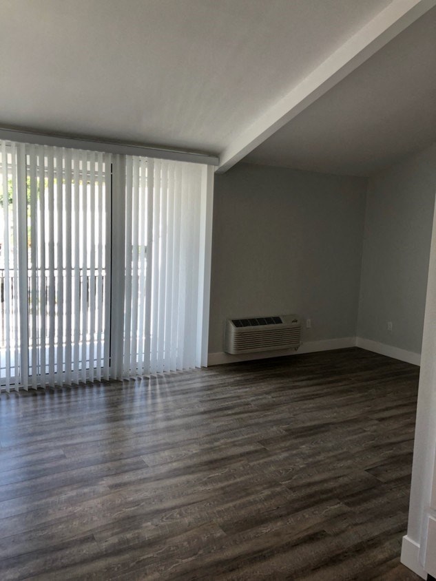 an empty living room with wood flooring and sliding glass doors