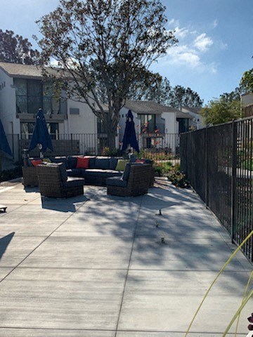 a patio with furniture and a black fence