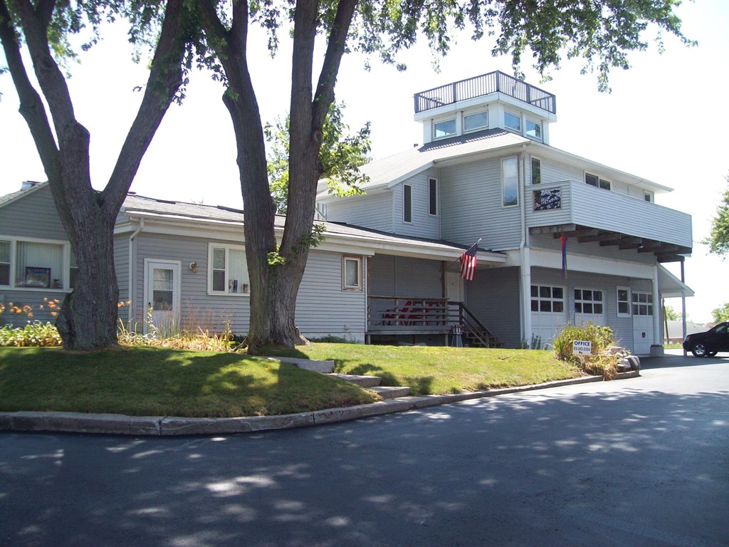 the front of a white house with a porch and a tree