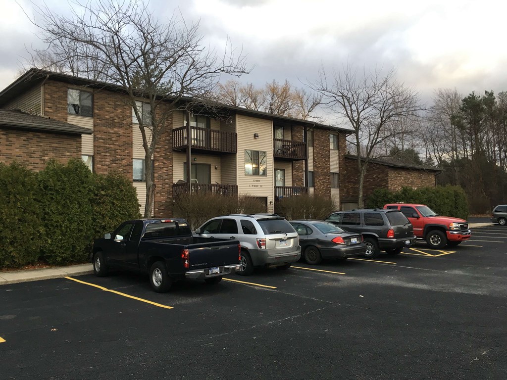 a parking lot full of cars in front of an apartment building