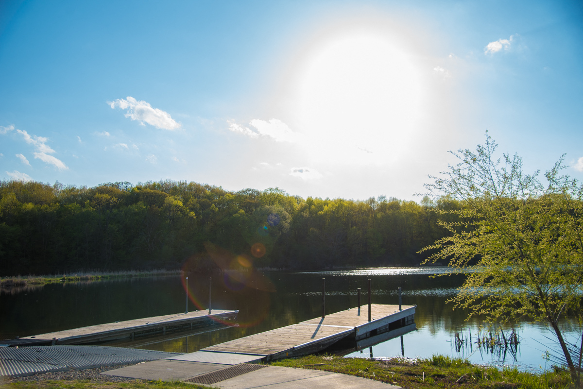 a dock on a lake with the sun shining over the water