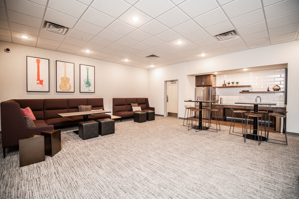 a lounge area with couches and tables in a room with a kitchen