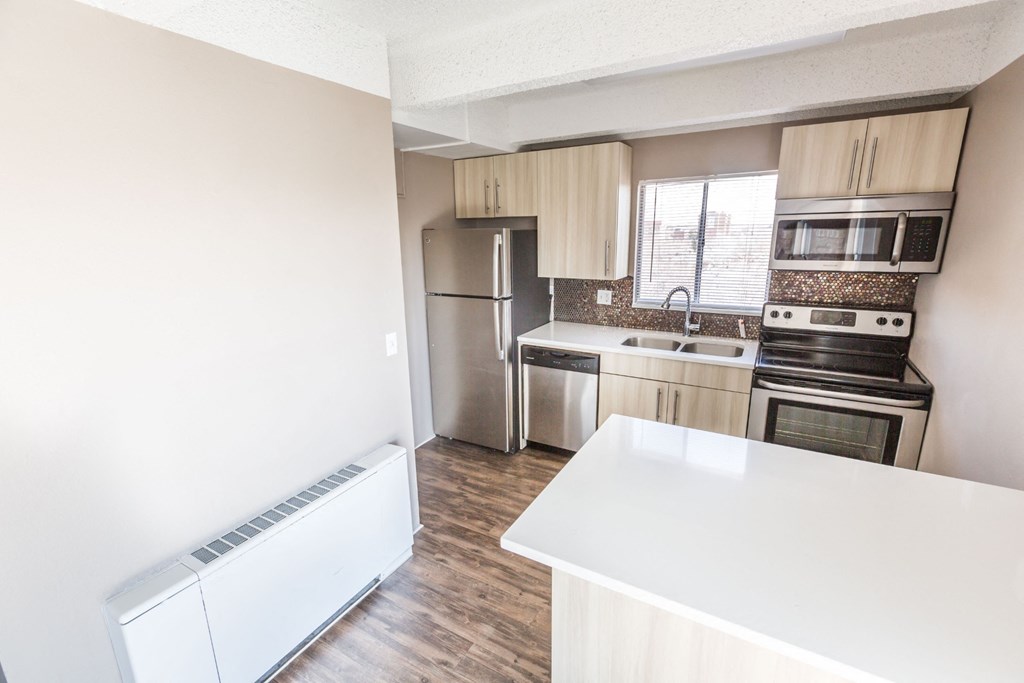 a kitchen with a white counter top and a stainless steel refrigerator