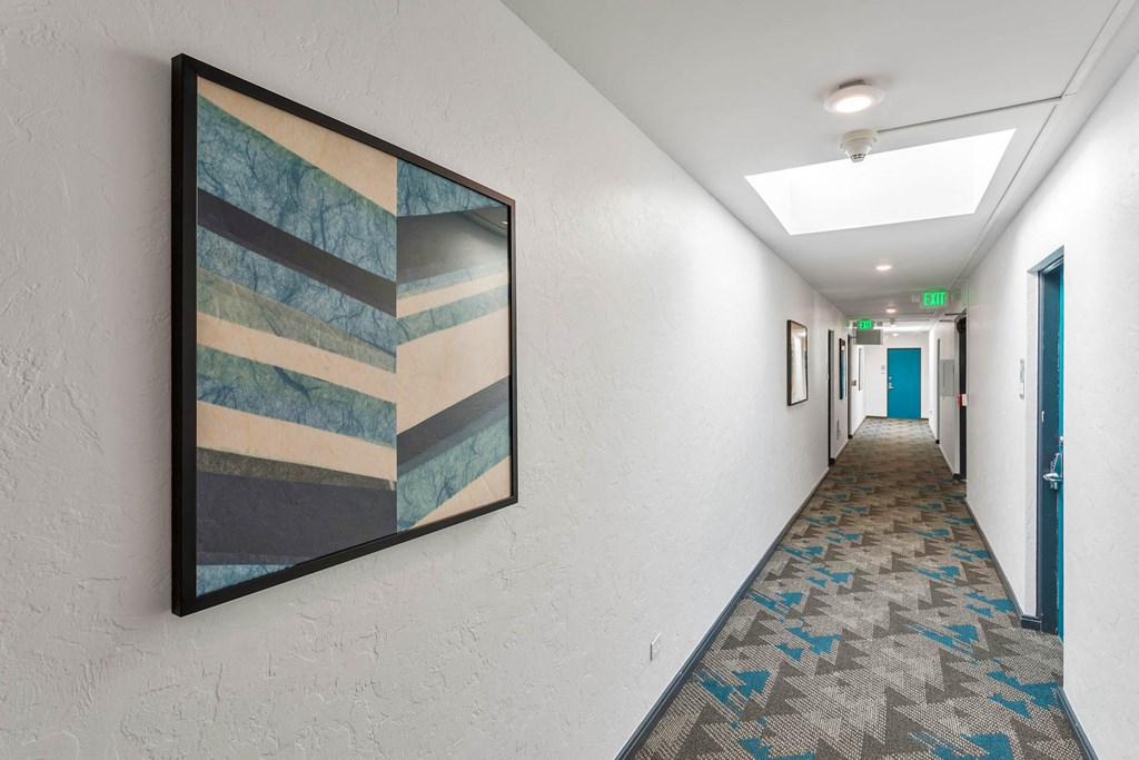 a long hallway with a painting on the wall and a corridor with doors
