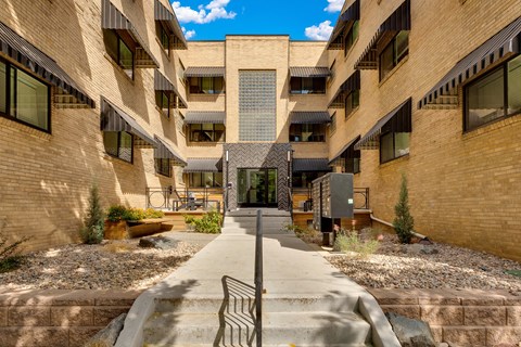 A courtyard surrounded by buildings with a metal bench in the middle.