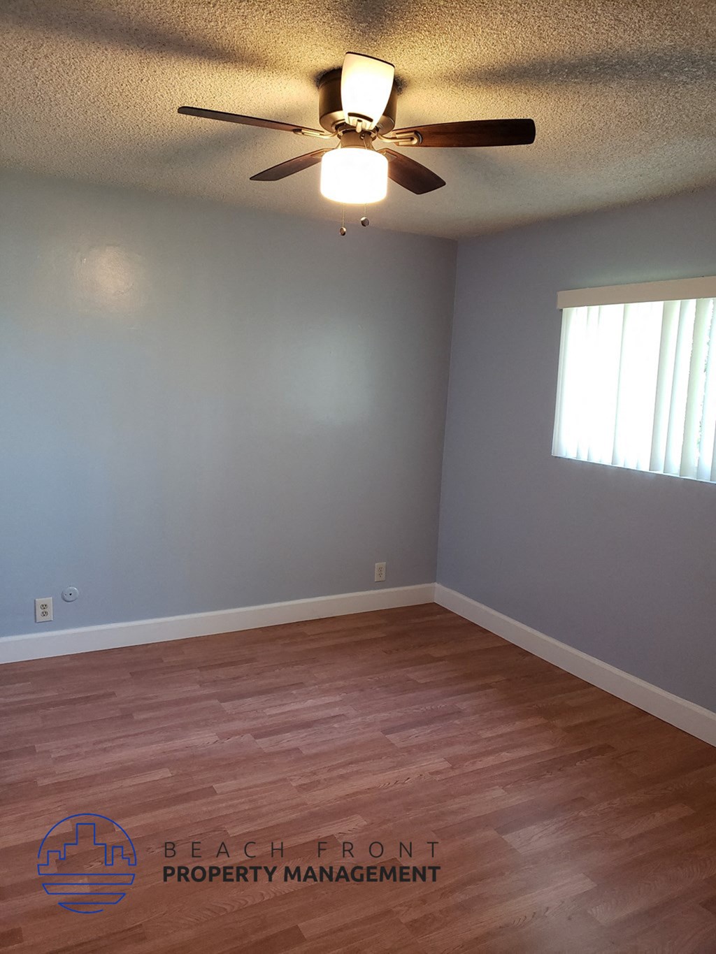 an empty living room with wood floors and a ceiling fan