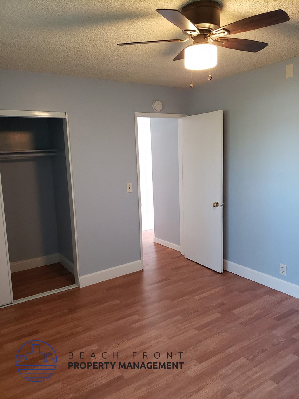 an empty living room with wood floors and a ceiling fan