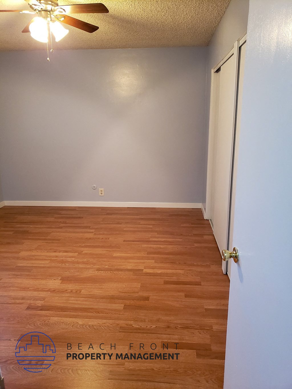 an empty room with wooden floors and a ceiling fan
