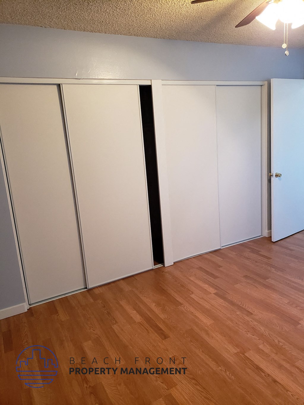an empty room with a wood floor and white closets