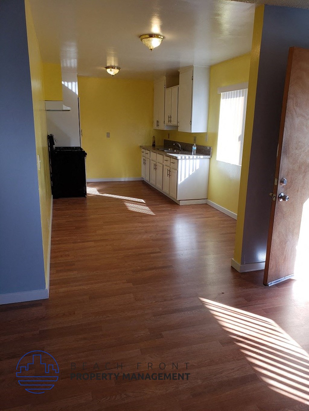 an empty kitchen with yellow walls and a wooden floor