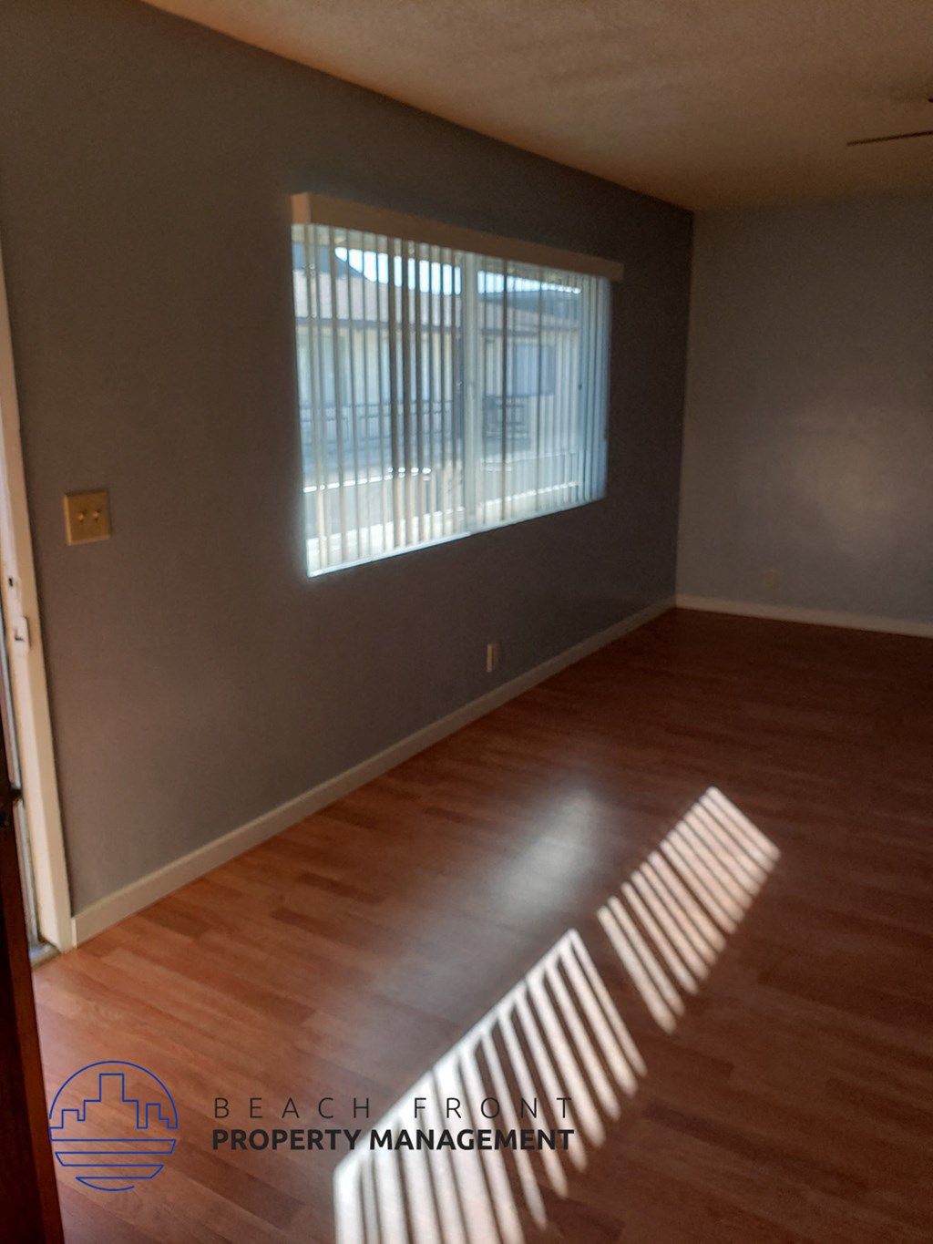 an empty living room with wood floors and a window