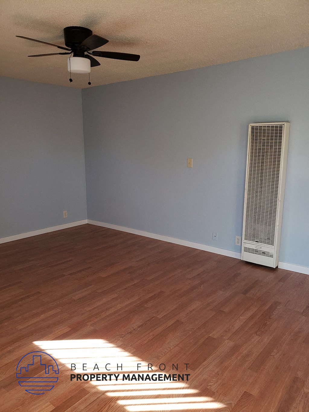 an empty living room with wood floors and a ceiling fan