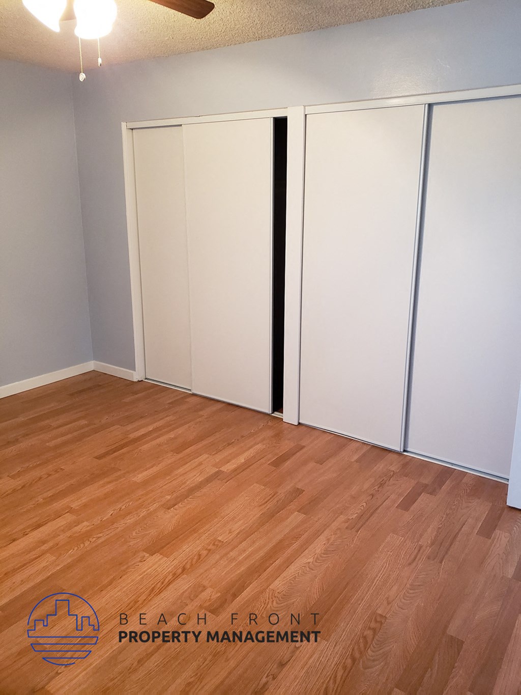 an empty room with wood flooring and white closet doors