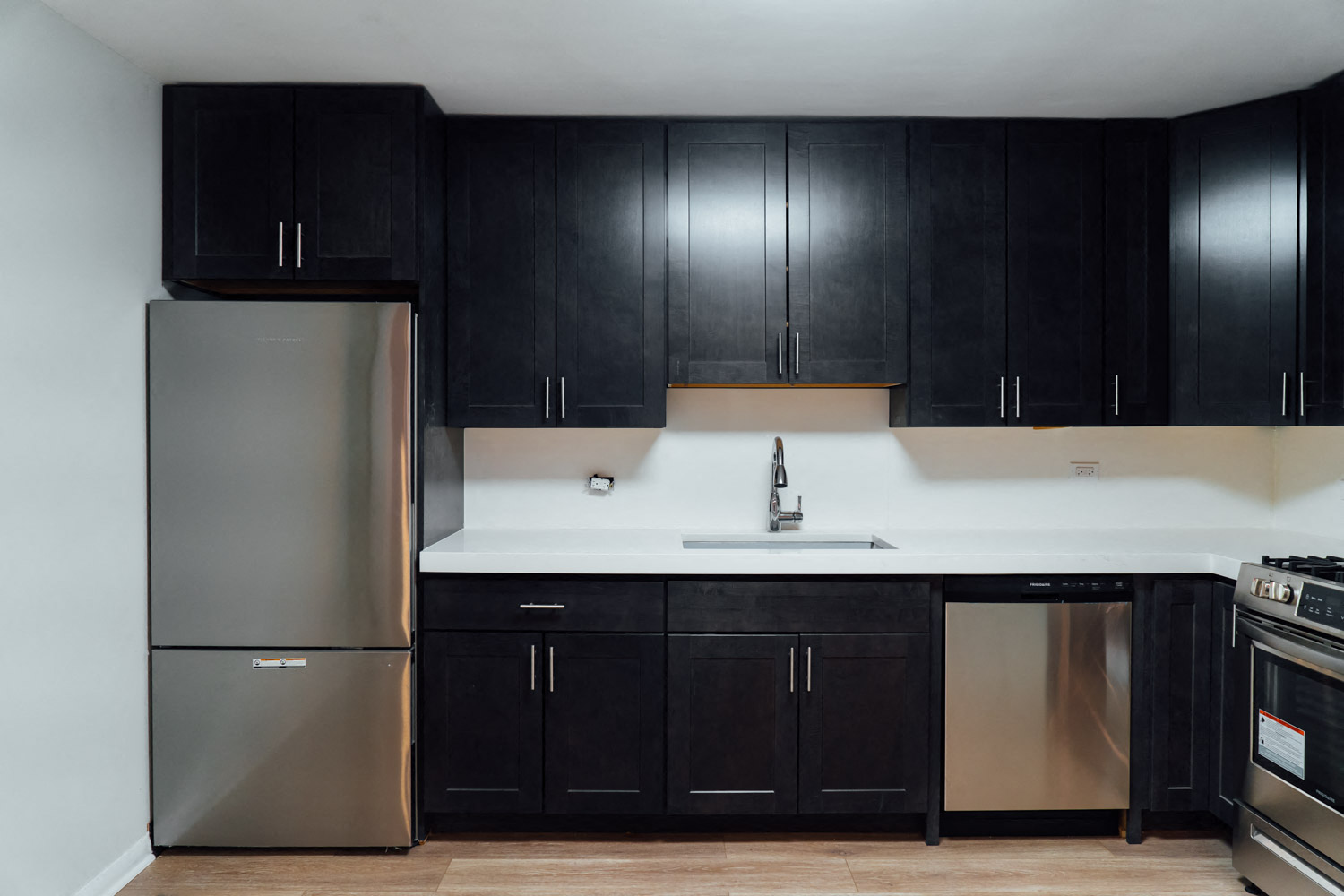 a kitchen with black cabinets and a stainless steel refrigerator