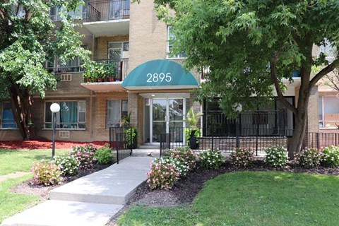 an apartment building with a green awning and a tree in front