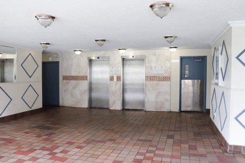 a large room with four elevators and a tile floor