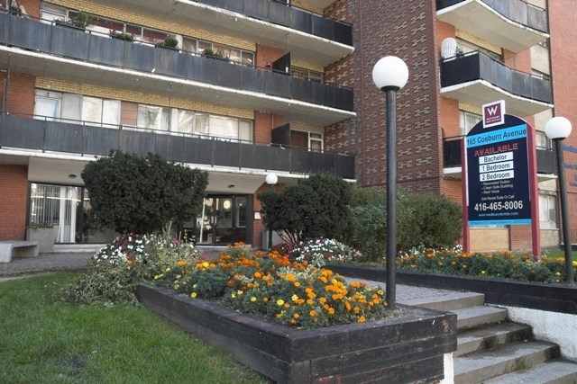 an apartment building with a sign in front of a flower garden