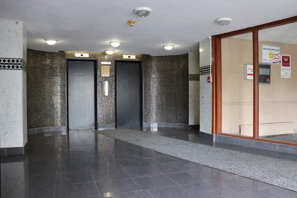 the lobby of a building with four elevators and a stone bench