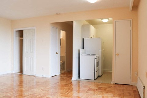 an empty living room with a refrigerator and a door
