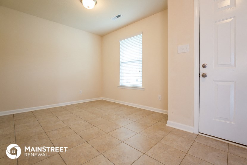the spacious living room with tile flooring and a white door